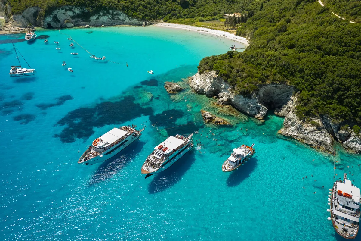 Aerial view of boats anchored off the green coast of Antipaxos