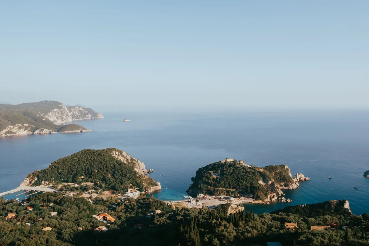 Aerial view of a Corfu coastline covered in dense green trees