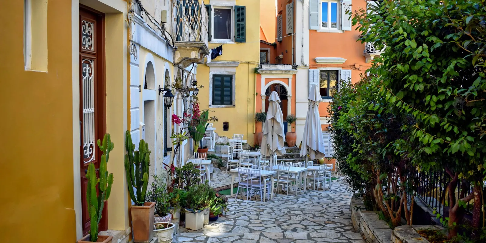 Narrow street in Corfu Old Town with cafés and tall shuttered buildings