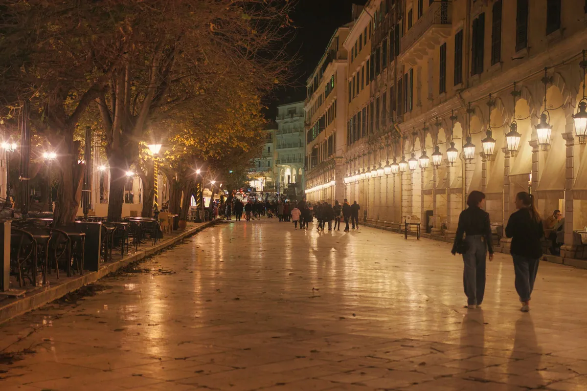 The Liston arcade in Corfu Town lit up at night with people walking