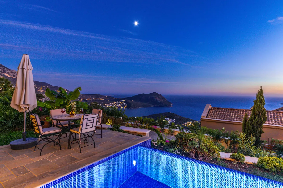 Pool terrace with table and chairs overlooking the sea in the evening